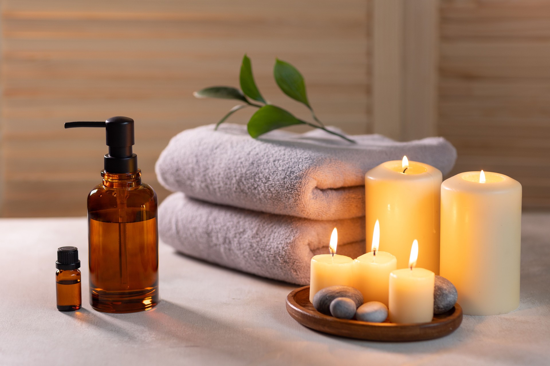 Artículos de tratamiento de spa de belleza sobre mesa de madera blanca. Velas, piedras, aceites esenciales y toallas. Baño acogedor.
